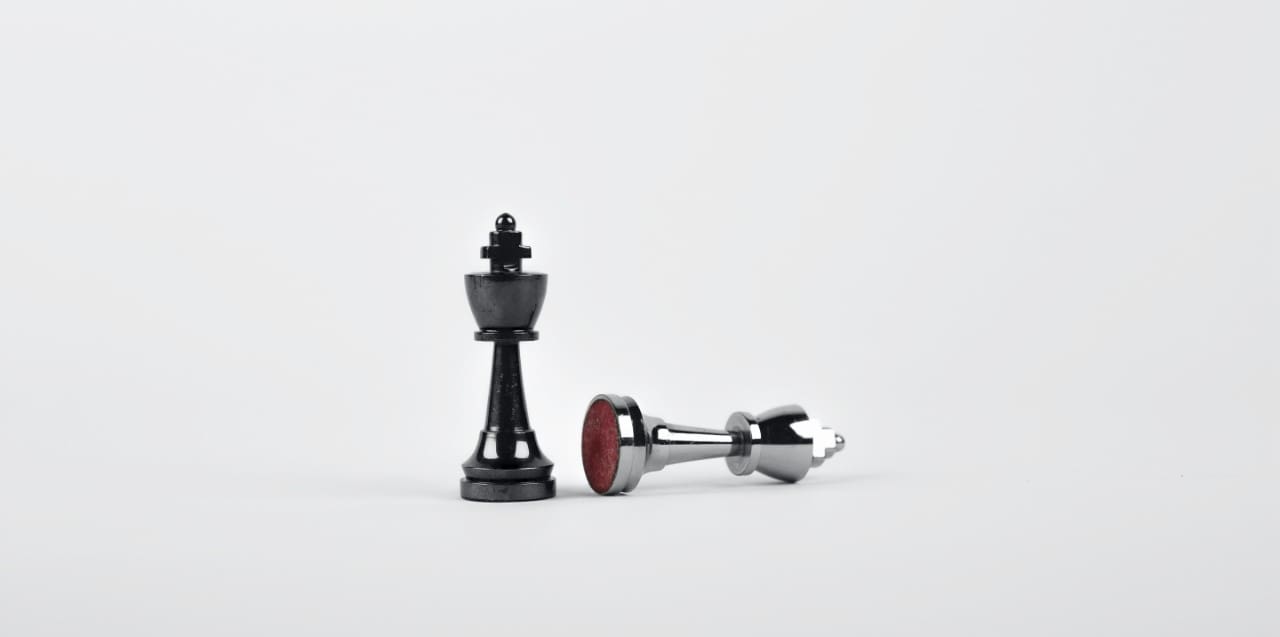 A black chess king stands tall, while a silver chess king is toppled over, representing the disruption and loss caused by trafficking in stolen property.
